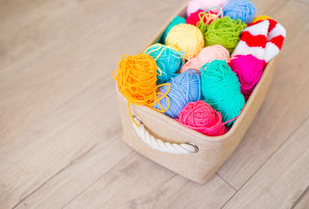 Bright colored threads for knitting in a basket on a wooden background.の写真素材