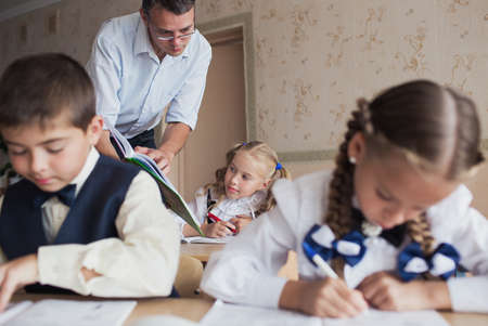 a teacher at school teaches children, carefully reads them a book. Students write in a notebookの写真素材