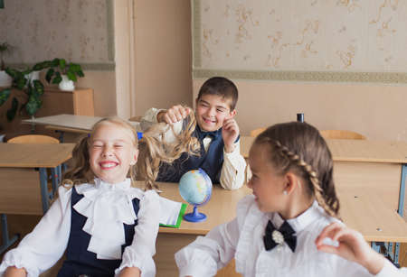 a boy at school pulls girls' pigtails, girls cry out in discontent.の写真素材