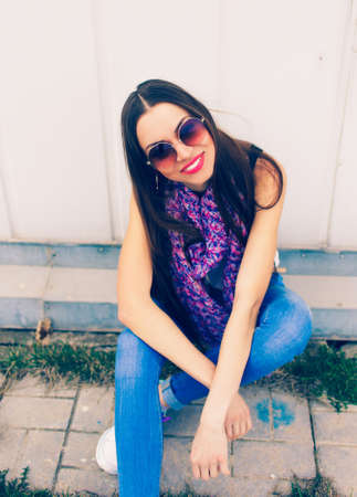 a young girl in large round glasses stands against a blue wall.の写真素材