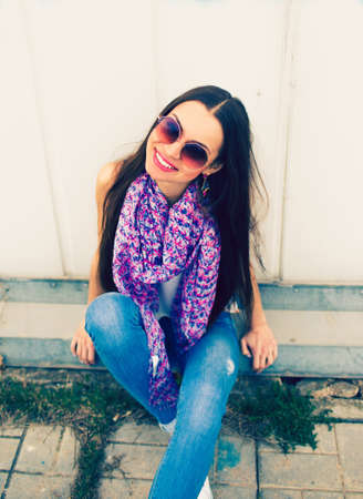 a young girl in large round glasses stands against a blue wall.の写真素材