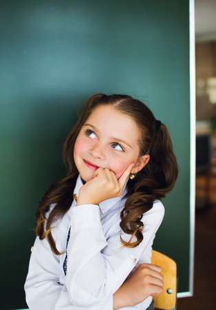Schoolgirl near the blackboard in a white shirt and tie