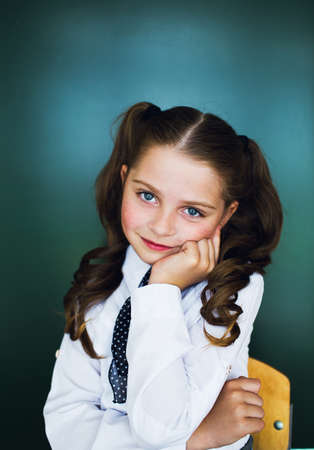 Schoolgirl near the blackboard in a white shirt and tieの写真素材