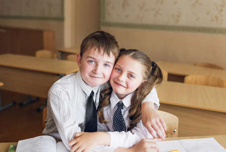 a boy and a girl students sit at a Desk in the classroom huggingの写真素材