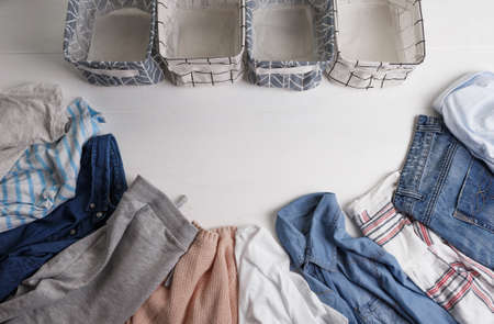 A group of organic cotton clothing set on a white table is ready to be folded into white baskets.The concept of closet organization. Colors in the Scandinavian style. Using the Komari method.の写真素材