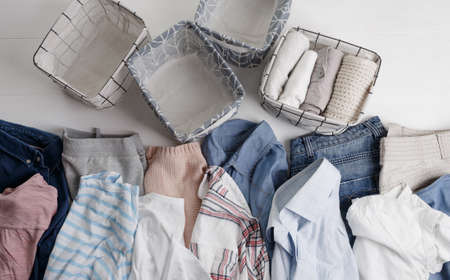 A group of organic cotton clothing set on a white table is ready to be folded into white baskets.The concept of closet organization. Colors in the Scandinavian style. Using the Komari method.の写真素材