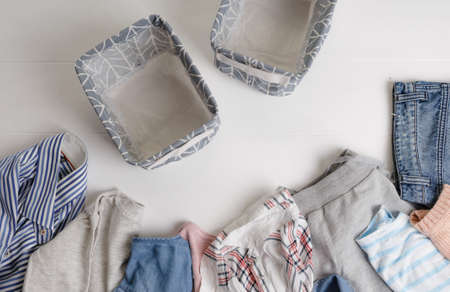 A group of organic cotton clothing set on a white table is ready to be folded into white baskets The concept of closet organization. Colors in the Scandinavian style. Using the Komari methodの写真素材