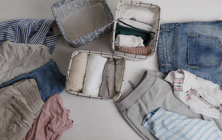 A group of organic cotton clothing set on a white table is ready to be folded into white baskets The concept of closet organization. Colors in the Scandinavian style. Using the Komari methodの写真素材