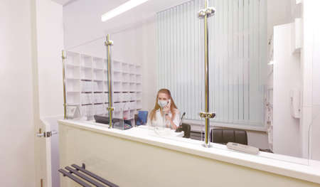 Girl-administrator in a white coat and mask of a medical clinic.reception of patients.Admission to the hospitalの写真素材