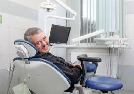 a male patient lies in the dentists chair and smiles.の写真素材