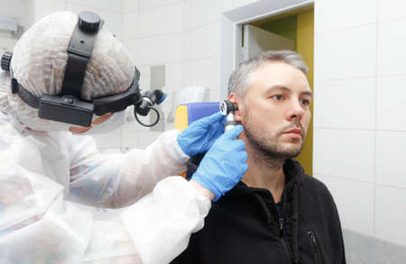 Profile photo of an otolaryngologist holding an Otoscope to a patients earの写真素材