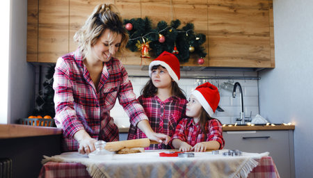 mom teaches her daughters in the kitchen to make a delicious dessert out of dough.の写真素材