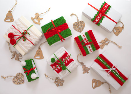 Christmas boxes are decorated with knitted ribbons. wooden toys for the Christmas tree. Isolated white background top view. Red, green ornament.の写真素材