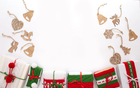 Christmas boxes are decorated with knitted ribbons. wooden toys for the Christmas tree. Isolated white background top view. Red, green ornament.の写真素材