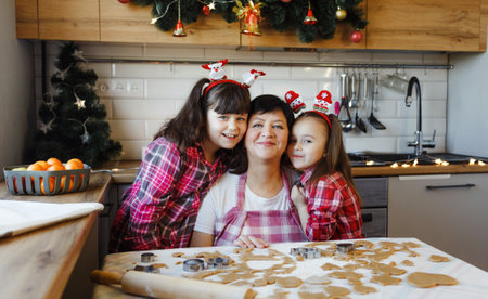a grandmother and two granddaughters hug in the kitchen on the eve of Christmas. Everyday lifestyle in the interior from real lifeの写真素材
