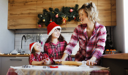 Mom and daughters learn how to make cookies in the kitchen decorated for Christmasの写真素材