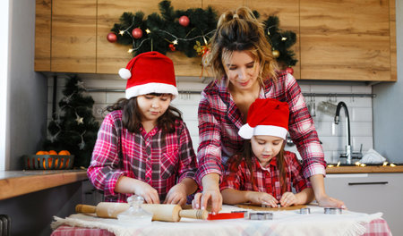Mom and daughters learn how to make cookies in the kitchen decorated for Christmasの写真素材