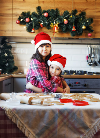 two teenage girls in Christmas hats hug each other in the kitchen in the run-up to Christmas.の写真素材