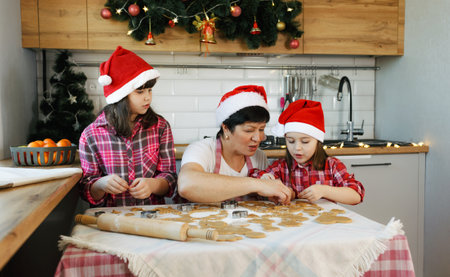 a grandmother and two granddaughters prepare cookies in the kitchen in the run-up to Christmas. Everyday lifestyle in the interior from real lifeの写真素材