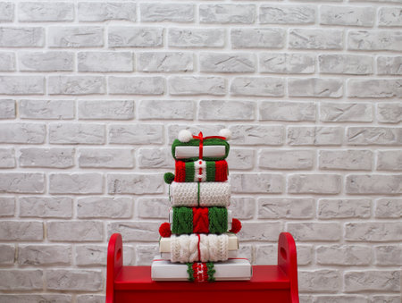 Christmas gifts in bright ribbons are stacked against a brick wall. Red and green ribbons with ornaments.の写真素材