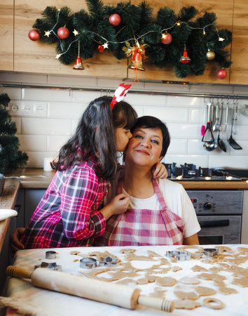 Granddaughter kisses her grandmother in the kitchenの写真素材