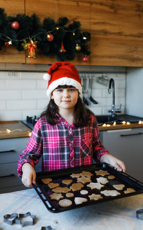 a girl in the kitchen holds a tray of cookies in her handsの写真素材