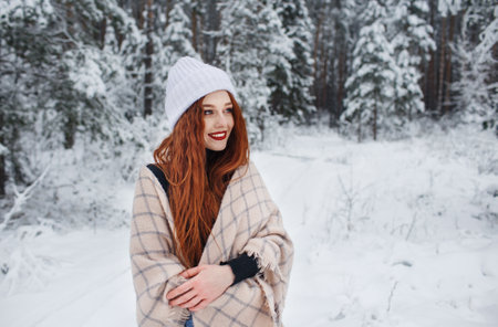 A young girl with long bright red hair on a winter background.A red-haired woman in a white cap.の写真素材
