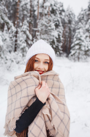 A young girl with long bright red hair on a winter background.A red-haired woman in a white cap.の写真素材