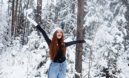 Young red-haired girl with long red hair on a winter background.Red-haired woman in a white hat on the background of winter nature.の写真素材