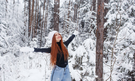 Young red-haired girl with long red hair on a winter background.Red-haired woman in a white hat on the background of winter nature.の写真素材