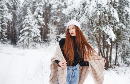A young girl with long bright red hair on a winter background.A red-haired woman in a white cap.の写真素材