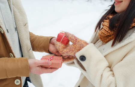 a guy gives a gift to a girl in a snow-covered forest. Surprise for Valentines Dayの写真素材