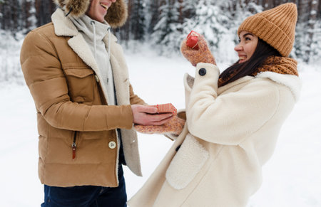a guy gives a gift to a girl in a snow-covered forest. Surprise for Valentines Dayの写真素材