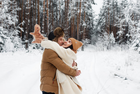 A young happy couple embrace in a snow-covered forest. Happy weekend. Valentines Dayの写真素材