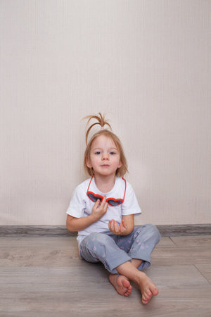 little girl B is sitting on the floor of the room against the wall.の写真素材