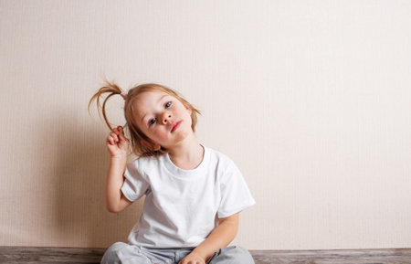 little girl B is sitting on the floor of the room against the wall.の写真素材