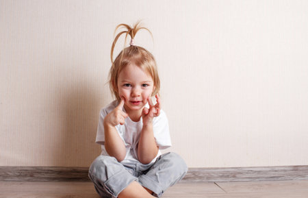 little girl B is sitting on the floor of the room against the wall.の写真素材