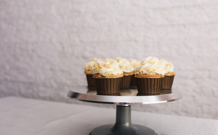 the chef girl sprinkles icing on fresh cupcakes covered in vanilla cream.Sweet homemade cupcakes with cream on a tray. Food for breakfast. Freshly baked cupcakes for dessert. Foodies and cuisine.の写真素材