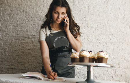 the cook girl is talking on the phone taking an order from a customer.の写真素材