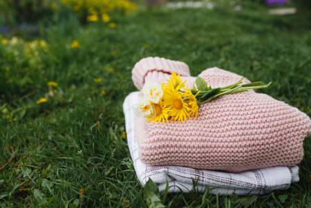 a bouquet of yellow flowers lies on top of neatly folded clothes on the green lawn. Spring mood.の写真素材