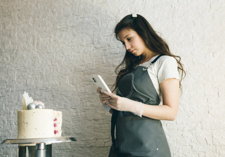 a young pastry chef girl takes pictures of a prepared cake.の写真素材