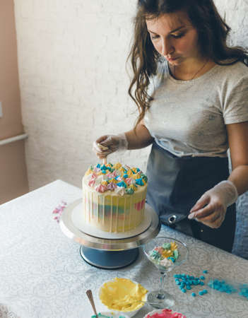 A pastry chef makes a wedding cake with her own hands and puts colorful decorations on the cakes with cream. Preparation for the celebrationの写真素材