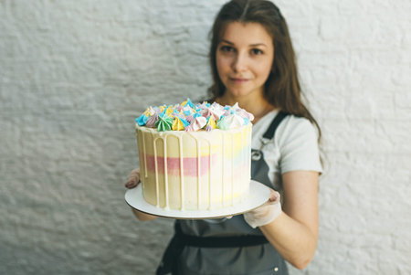 a pastry chef girl holds a prepared cake in her hands.の写真素材