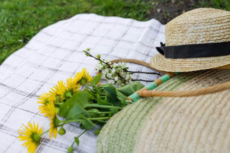 A bouquet of yellow flowers a straw hat and a straw bag lie on the tablecloth. Top view.の写真素材