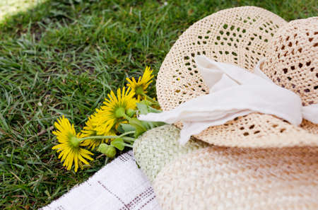A bouquet of yellow flowers a straw hat and a straw bag lie on the green lawn. Top view.の写真素材