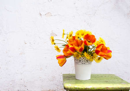 a bouquet of spring flowers in a white vase on a light background. Wooden stand.の写真素材