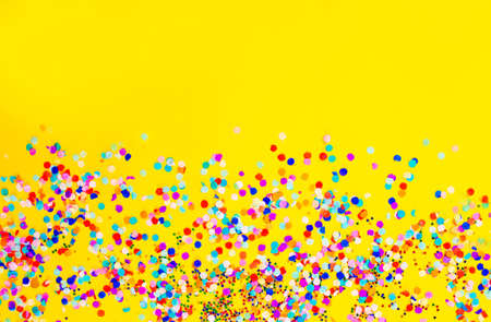 lots of colored confetti on a yellow background.の写真素材