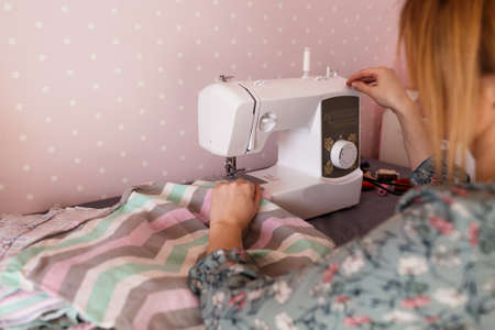 hands of a seamstress close up working at a sewing machineの写真素材
