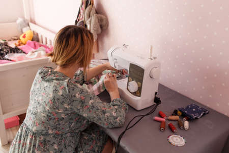 A woman sews at home for a sewing machine. Favorite hobby. Own production of clothing.の写真素材