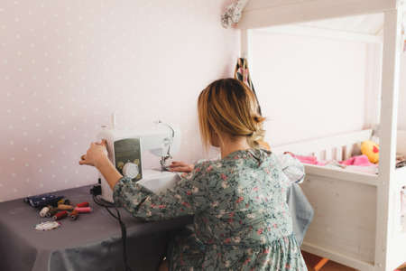 A woman sews at home for a sewing machine. Favorite hobby. Own production of clothing.の写真素材